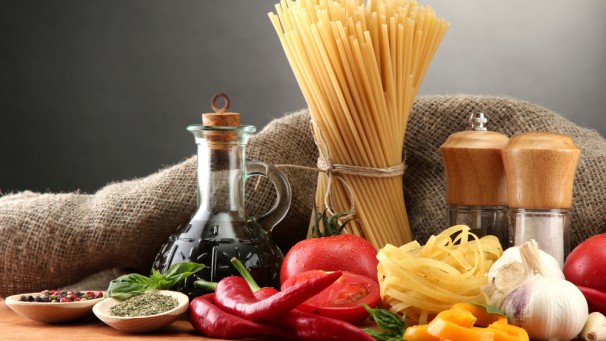 Pasta spaghetti, vegetables and spices, on wooden table, on grey background